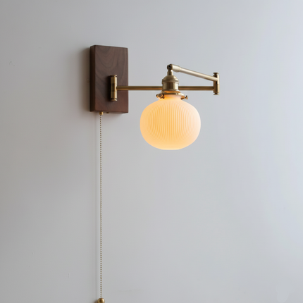 Walnut wall lamp with round ceramic shade and swiveling copper arm