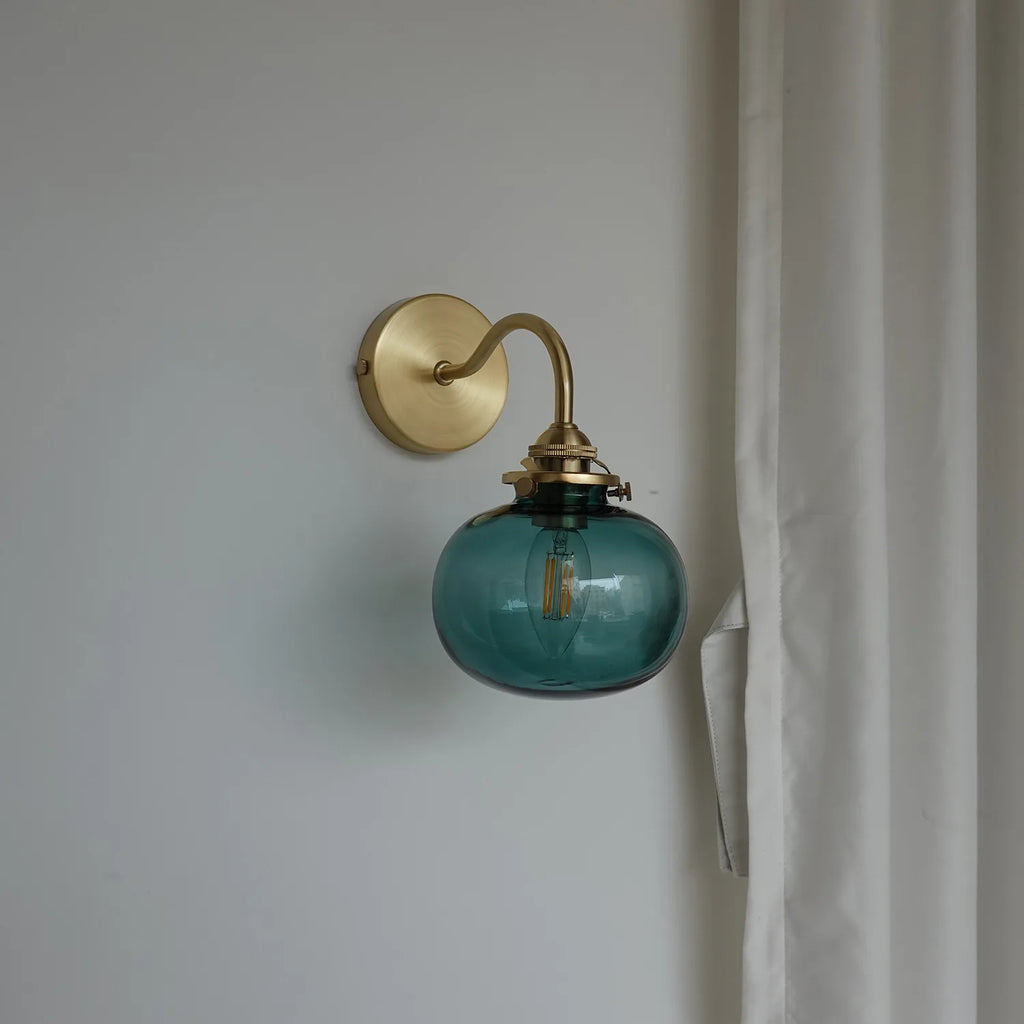 Blue-tinted glass ball wall light with elegant brass arc