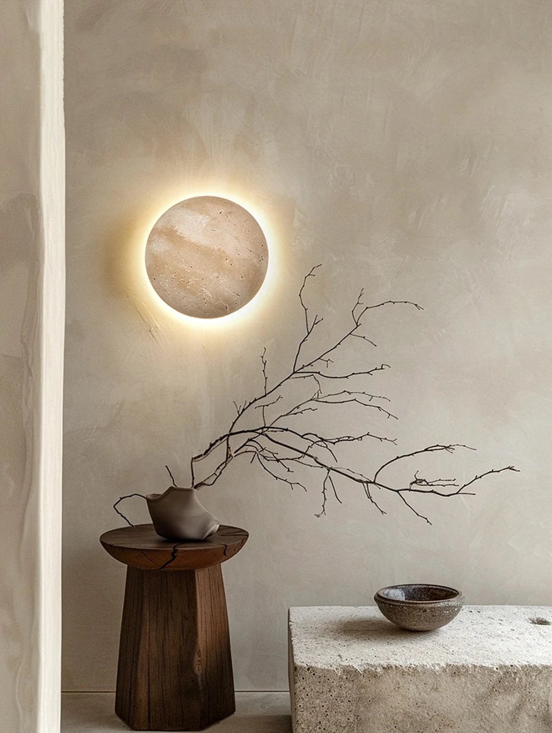 Round travertine wall light with warm backlighting in a natural stone look