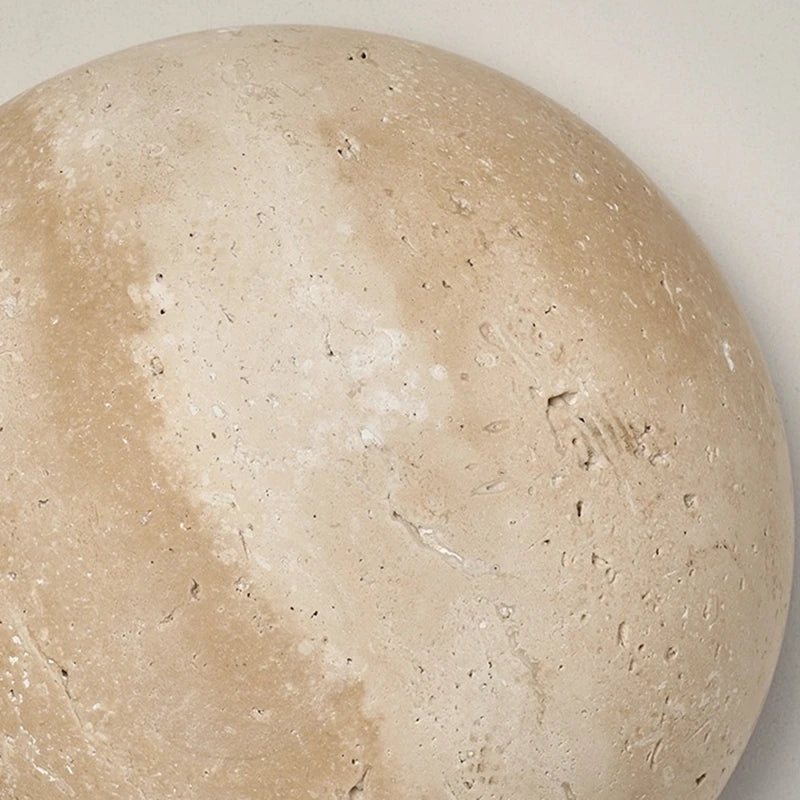 Round travertine wall light with warm backlighting in a natural stone look