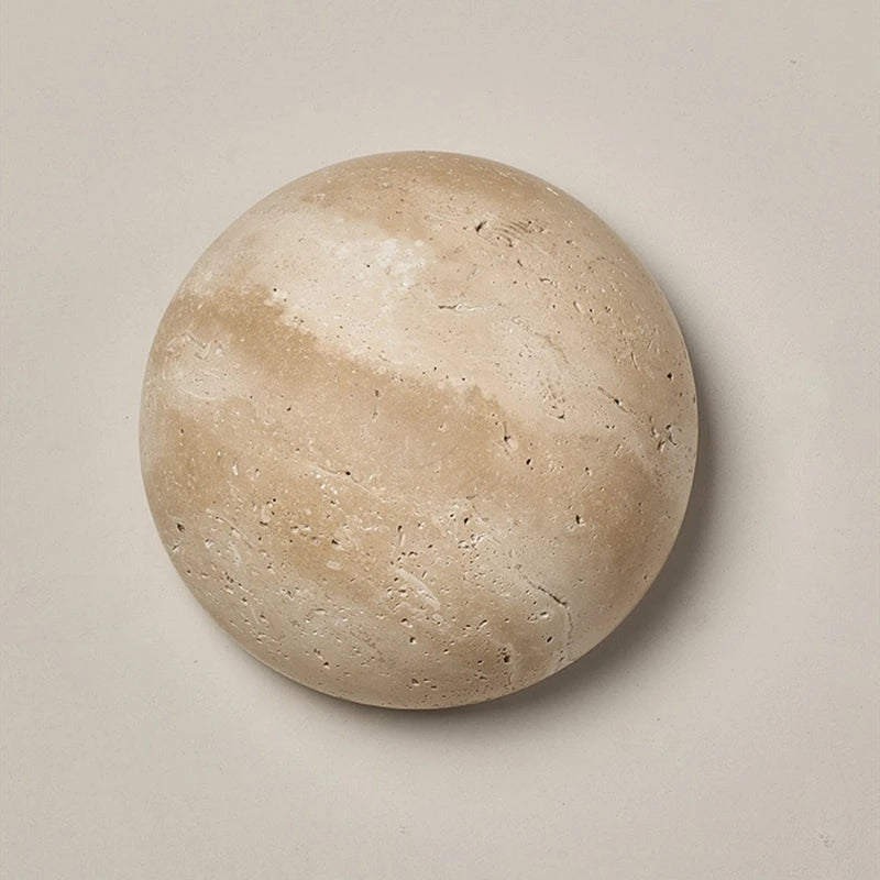 Round travertine wall light with warm backlighting in a natural stone look