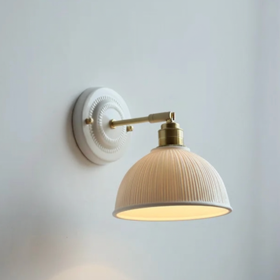 Wall lamp with round grooved ceramic shade and brass arm